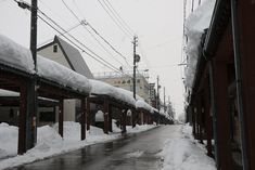 a street with snow on the ground and power lines in the background, along with buildings