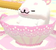 a white cat sitting in a pink bowl on top of a table