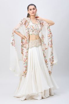 Ivory cape with multi colored floral, palm tree and butterfly pattern embroidery. Comes with matching embroidered blouse and embroidered yoke two tiered skirt. - Aza Fashions White Embroidered Dress With Cape Sleeves, Bohemian Fitted Sets With Cape Sleeves, White Traditional Dress With Cape Sleeves, Spring Cape Dress In White, White Cape Dress For Spring, White Lehenga For Wedding In Spring, White Wedding Lehenga For Spring, White Spring Wedding Lehenga, White Lehenga For Spring