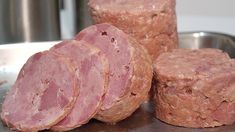 three pieces of meat sitting on top of a metal tray next to a silver bowl