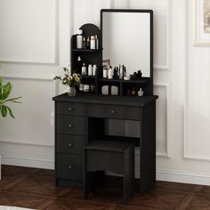 a black vanity with mirror and stool next to it on a wooden floor in front of a white wall