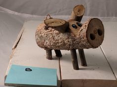 a wooden toy sheep sitting on top of a piece of wood