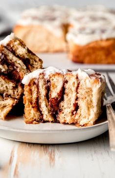 two pieces of cinnamon roll on a plate with fork and knife next to the cake