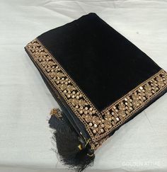 a black book with gold trim and tassels on the cover is sitting on a white sheet