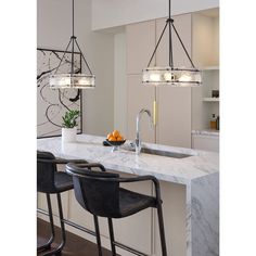 a kitchen with marble counter tops and bar stools next to an island that has two lights hanging over it