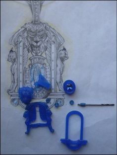 some blue plastic objects are laying on a white surface and there is a drawing behind them