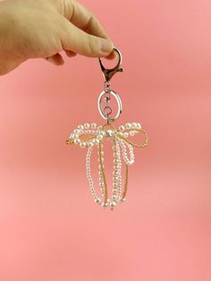 a hand holding a keychain with pearls and a dragonfly on the front