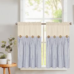 a blue and white striped curtain hanging in front of a window next to a potted plant