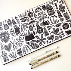 two pencils are sitting next to a drawing book with black and white designs on it