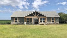 a large gray house sitting on top of a lush green field