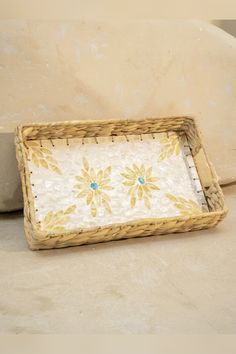 a wicker tray with flowers painted on the bottom and gold trim around the edge