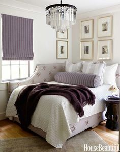 a bedroom with a bed, chandelier and pictures on the wall above it