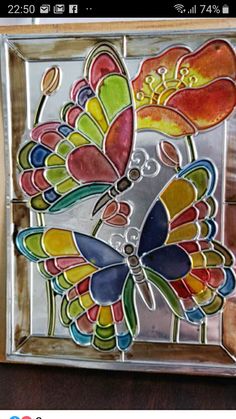 a colorful glass butterfly sitting on top of a wooden table