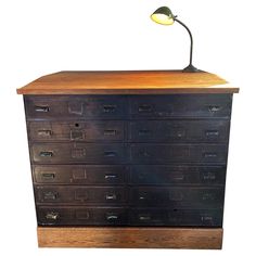 an old wooden dresser with drawers and a lamp on it's top, against a white background