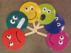 a group of different colored paper plates with eyes and mouths on top of each other