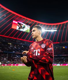 a soccer player is standing on the field in front of an empty stadium at night