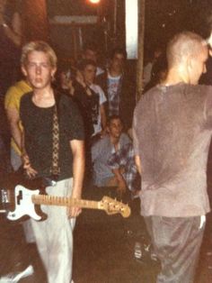 a group of people standing next to each other in front of a man with a guitar