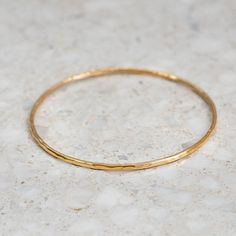 This fine hand forged bangle has a hammered finish. Beautiful worn on its own, or layered with our other fine bangles. Approx. width: 2mm. Approx. gold weight: 7 grams in 9ct.