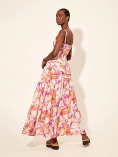 Experience the beauty of a garden in full bloom with the Kivari Nadia Strappy Maxi Dress. Featuring a vibrant watercolour floral print in shades of fuchsia, lilac, and citrus, this dress is made of 100% cotton voile for a lightweight and comfortable fit. The shirred bodice to hip and adjustable tie shoulder straps ensure a flattering and customizable fit, while delicate ruffle and frill details add a feminine touch. Complete your look with picot edges for a sweet and stylish finish. Fabric & Care 100% Cotton Voile Hand wash cold Line dry Strappy Maxi Dress, Garment Care Labels, Watercolor Floral Print, Sweater Tank Top, In Full Bloom, Cotton Voile, Dress Romper, Active Wear Tops, Dresses Xs