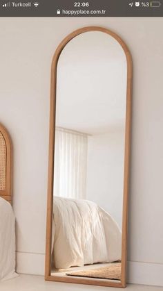 a large wooden mirror sitting on top of a white floor next to a bed in a room