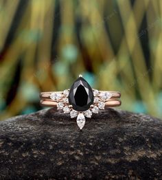 a black and white diamond ring sitting on top of a rock with leaves in the background