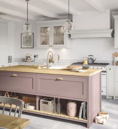 a kitchen with pink cabinets and an island in the middle, surrounded by glass globes