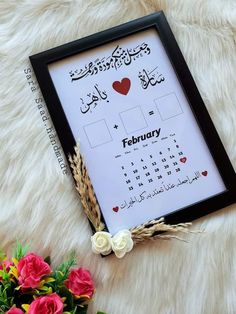 a framed calendar with arabic writing and flowers