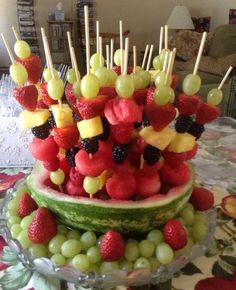 a cake made to look like fruit is on top of a plate with strawberries and grapes