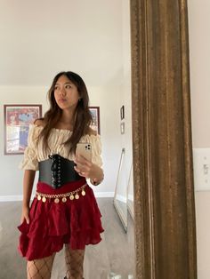 a woman taking a selfie in a mirror wearing a red skirt and black corset