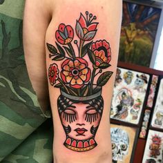 a woman's arm with flowers in a vase on it