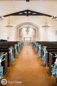 the interior of a church with pews decorated for a wedding ceremony and greenery