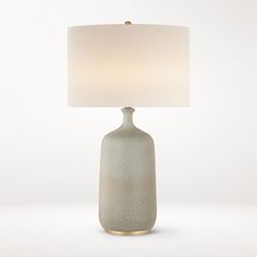 a white table lamp with a beige shade on the base and a gold trim around it