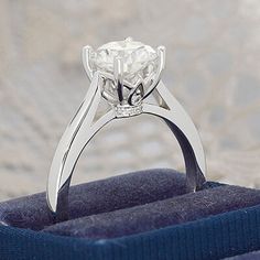 a diamond ring sitting on top of a blue velvet box