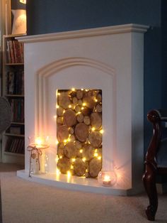 a fire place with logs and lights on the mantle in front of a bookcase