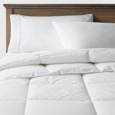 a bed with white sheets and pillows on it