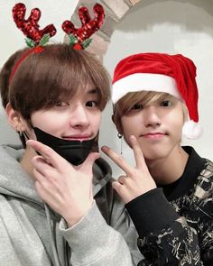 two young men with christmas hats on their heads