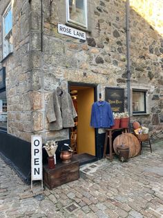 an open shop on the side of a stone building with clothes hanging out to dry