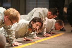 a group of men doing push ups on their stomachs in the middle of a line