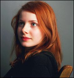 a woman with red hair is looking at the camera