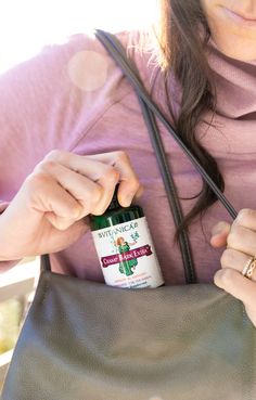 a woman holding a brown purse with a medicine bottle in her pocket and the other hand on top of it