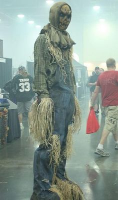 a scarecrow is standing in the middle of a room with people walking around it