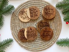 four wooden magnets on a wicker plate with pine branches and decorations around them