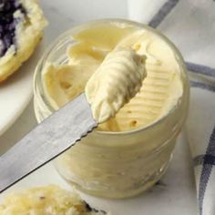 a jar filled with blueberry cheesecakes next to a knife