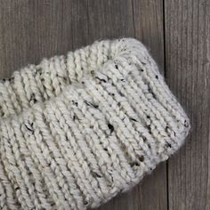 a white knitted mitt laying on top of a wooden floor