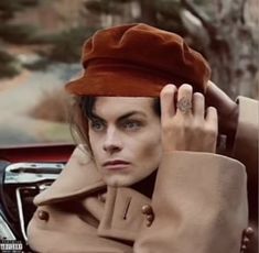 a woman wearing a red hat sitting in a car with her hand on her head