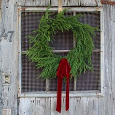 a green wreath with red ribbon hanging on an old door