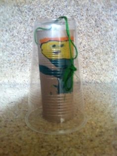 a plastic cup with an image of a teddy bear on the bottom and green string attached to it