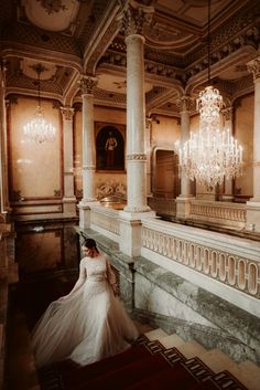 a woman in a wedding dress is sitting on the floor next to a chandelier