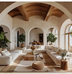 a living room filled with lots of white furniture and plants on top of it's walls