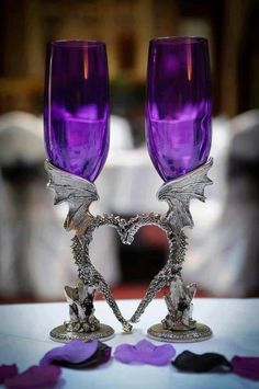 two purple wine glasses sitting on top of a table